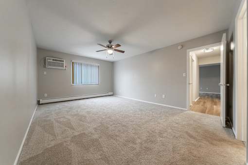 A room with a ceiling fan and carpeted floor.
