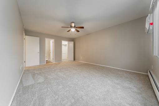 Empty room with a ceiling fan and carpeted floor.