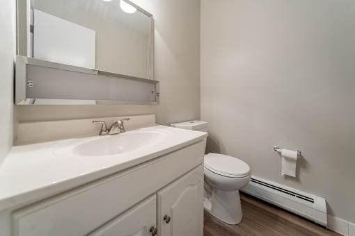 A white bathroom with a toilet, sink, and mirror.