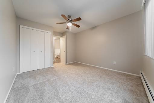 A room with a ceiling fan and carpeted floor.
