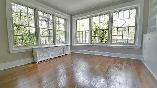 A room with a wooden floor and three windows at Integrity Gold Coast Apartments, Ohio, 44102