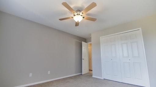 Apartment bedroom with carpeting and a ceiling fan light.