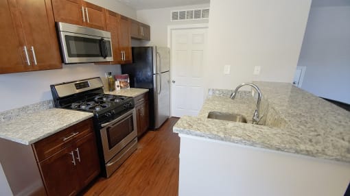 Townhome kitchen peninsula with granite counters, stainless steel appliances, and hardwood flooring.