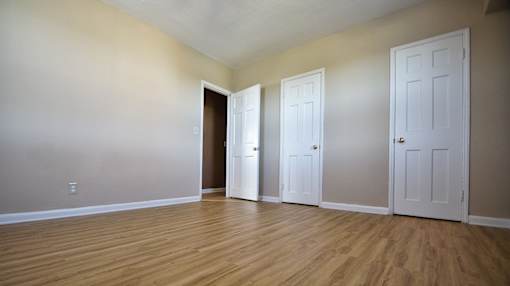 Three white doors are in a room  Integrity Realty, Cleveland, OHwith wood floors and beige walls.