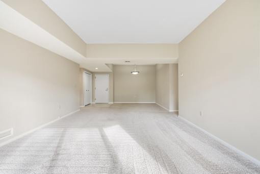 A spacious living room with a carpeted floor and white walls.at Atrium in The Village, Ohio