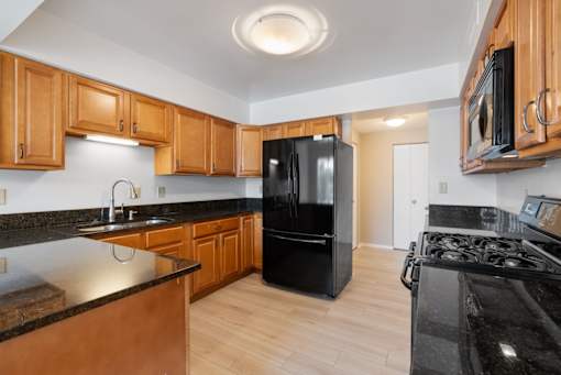 A kitchen with black appliances and wooden cabinets.at Atrium in The Village, Beachwood, 44122