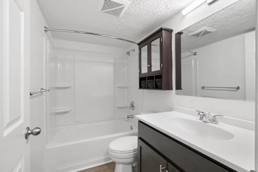 White bathroom with tub and espresso-colored cabinets at Integrity Medina Apartments, Medina, OH,  44256