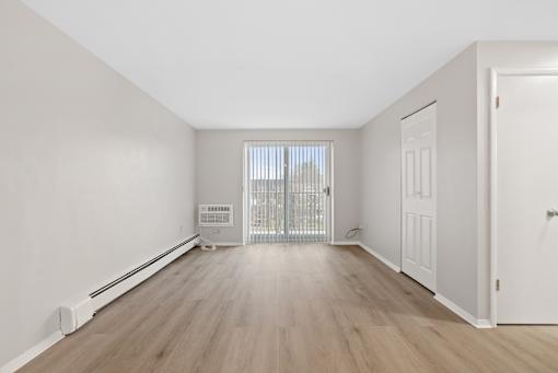Living room with ash wood floors and sliding door to balcony.