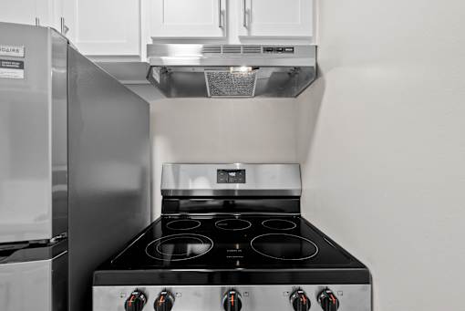 A modern kitchen with a stainless steel refrigerator and a black stove top.