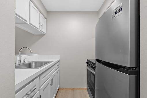 A kitchen with a stainless steel refrigerator and white cabinets.