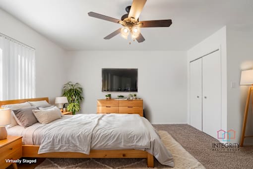 A bedroom with a bed, dresser, and ceiling fan.