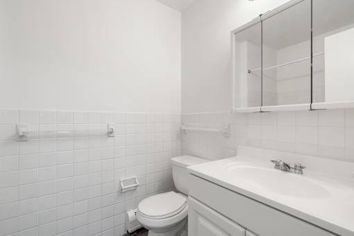Updated Wynwood bathroom with white cabinets, counters, and tiling.