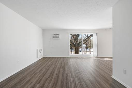 Updated Wynwood great room with sliding glass door to balcony and plank flooring.
