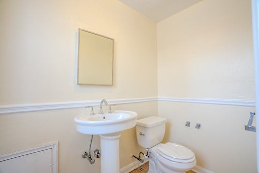 A bathroom with a toilet, sink and mirror.
