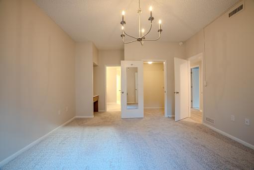 A large empty room with a chandelier and two doors.