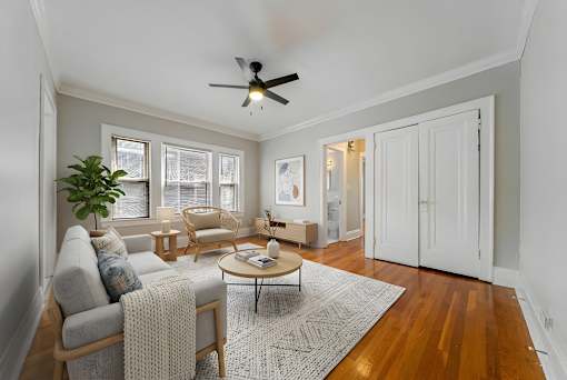 A living room with a ceiling fan and a grey sofa.