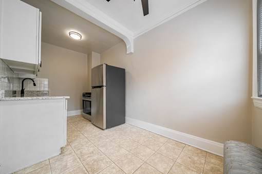 A kitchen with a refrigerator, a counter, and a fan.