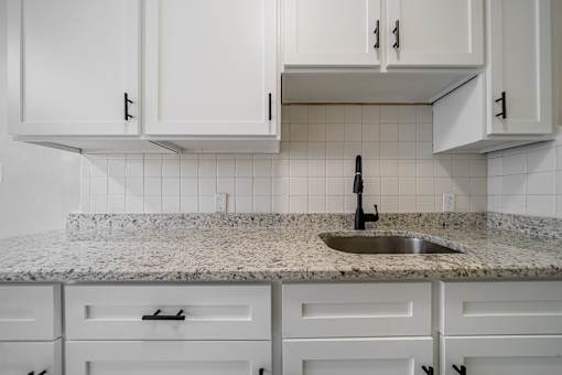 A kitchen with white cabinets and a granite countertop.