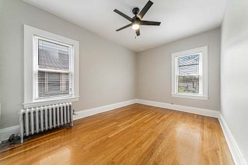 A bedroom with a bed, a ceiling fan, and a window with curtains.