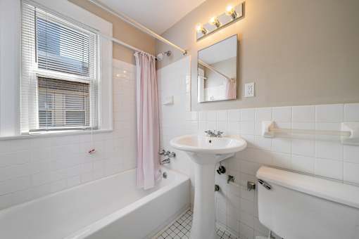A white bathroom with a pink shower curtain.