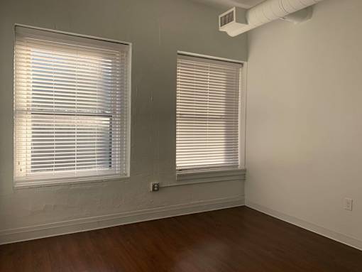 A room with two windows covered in white blinds.