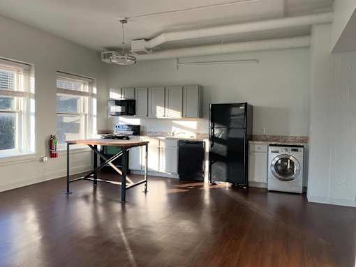 A kitchen with a table and a fridge.