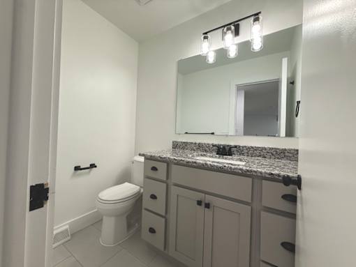 A bathroom with a toilet, sink, and mirror Old Green Place Apartments, Beachwood, OH