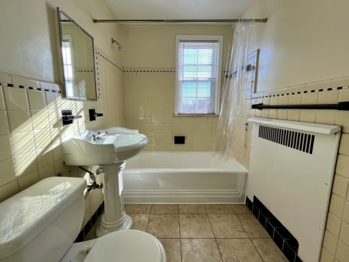 Tiled bathroom with white tub and standing sink.