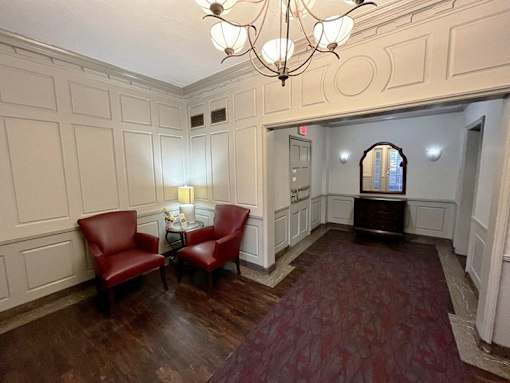 A room with a chandelier, two red chairs, and a table with a vase of flowers Integrity Realty, Cleveland, Ohio