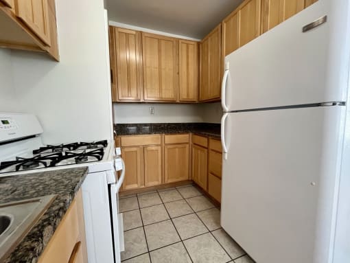 Empty kitchen with white appliances and wooden cabinets at Integrity Cleveland Heights, Cleveland Heights, 44106
