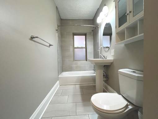 A white toilet sits in a bathroom with a white sink and a white bathtub at Integrity Cleveland Heights Apartments, Cleveland Heights, OH, 44106