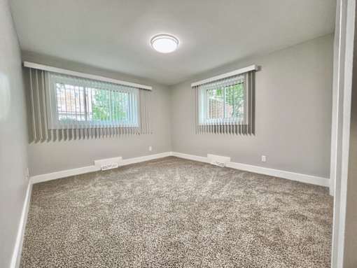 A room with a carpeted floor and two windows with blinds Old Green Place Apartments, Beachwood, OH