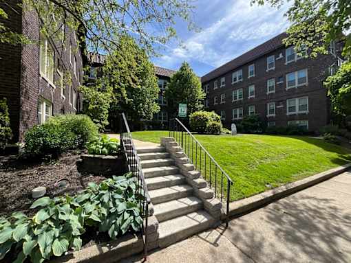 A set of stairs leads up to a grassy area in front of a brick building. at Integrity Cleveland Heights Apartments, Cleveland Heights, Ohio