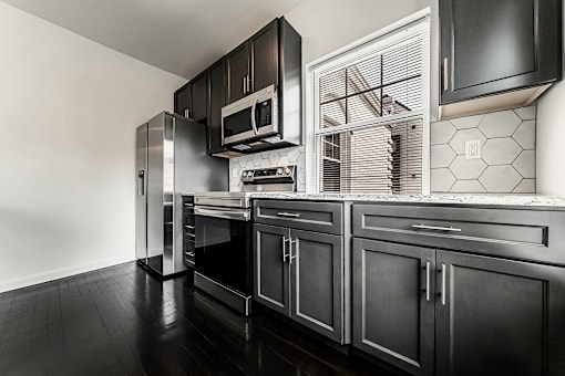 A black and white kitchen with a stainless steel refrigerator and oven.
