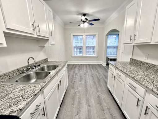 A kitchen with white cabinets and a marble countertop at Heights Collection Apartments, Ohio 44106