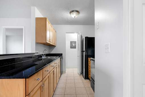 A kitchen with black countertops and wooden cabinets at Integrity Medina Apartments, Medina, OH,  44256