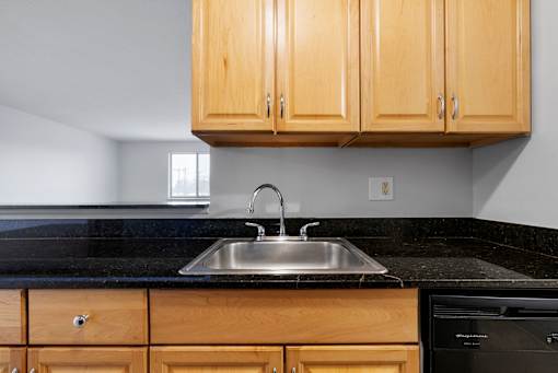 A kitchen with wooden cabinets and a black countertop at Integrity Medina Apartments, Medina, OH,  44256