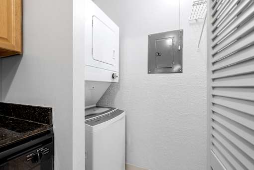 A white washing machine is in a small room with a metal vent on the wall at Integrity Medina Apartments, Medina, OH,  44256