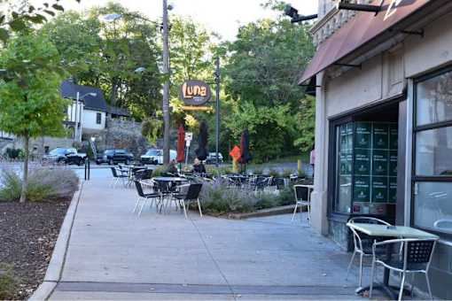 A restaurant named Luna is located in a green area with tables and chairs outside.