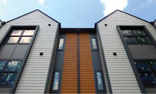 A modern house with a combination of grey and brown siding.