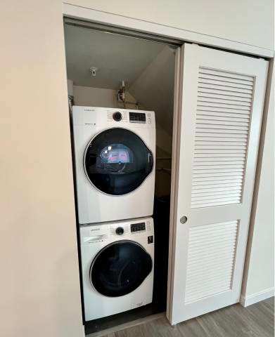 Two washing machines are stacked in a cabinet.