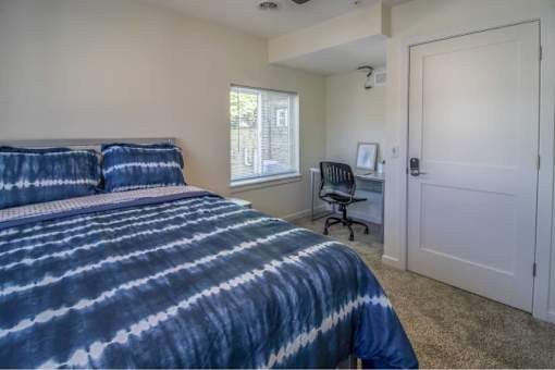 A bedroom with a bed, desk, and chair.