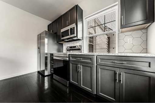 A black and white kitchen with a refrigerator, oven, and microwave.