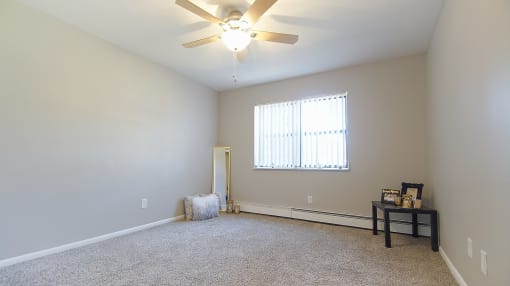 Carpeted apartment bedroom option with ceiling fan light.