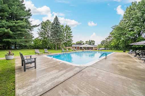 A large outdoor swimming pool surrounded by trees and a wooden deck.