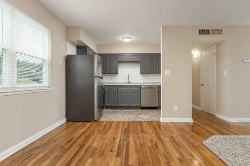 A kitchen with wooden floors and a black refrigerator.