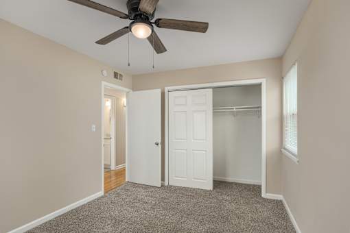 A room with a ceiling fan and a white door.