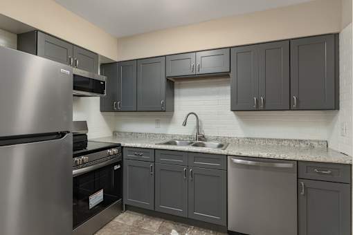 A kitchen with a stainless steel refrigerator, oven, and cabinets.