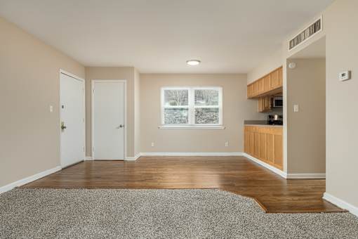 A room with a grey carpet and wooden flooring.