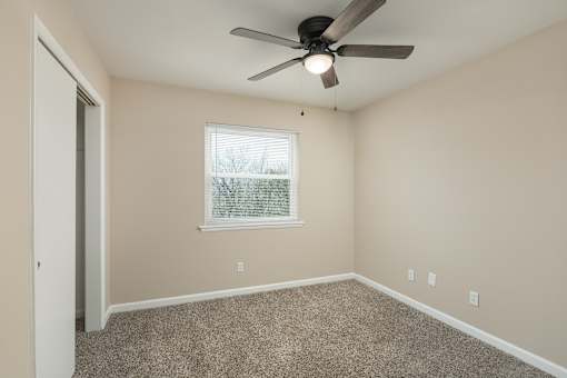 A room with a ceiling fan and a window.